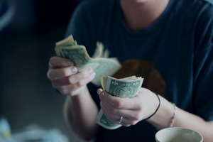 主婦Webライターの収入例⑤高額ジャンルへの転換で月収32万円を達成した主婦がお金を数えているイメージ