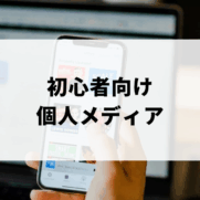 携帯を持ってパソコン作業をする男性